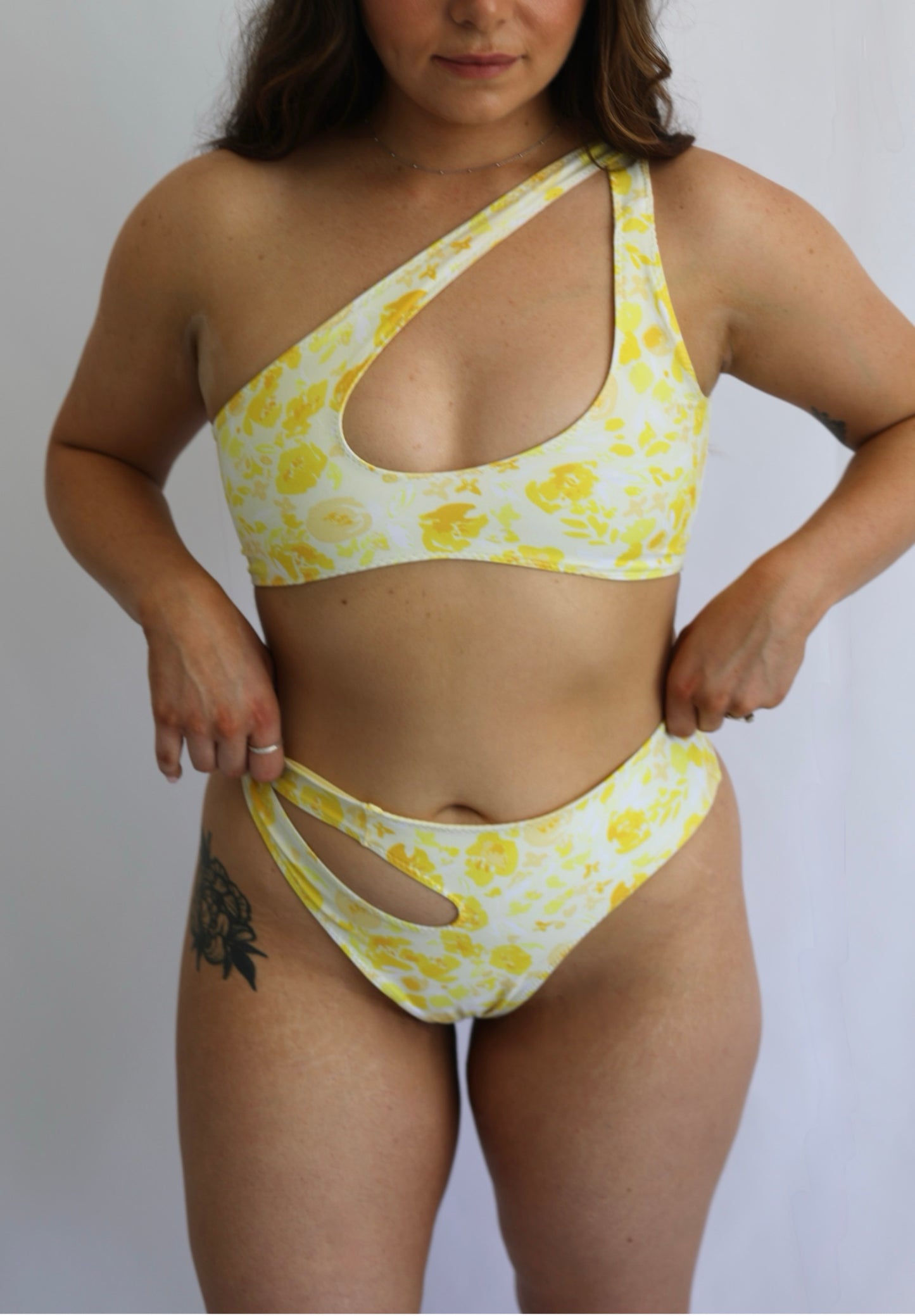 Woman wearing a yellow floral bikini against a plain background