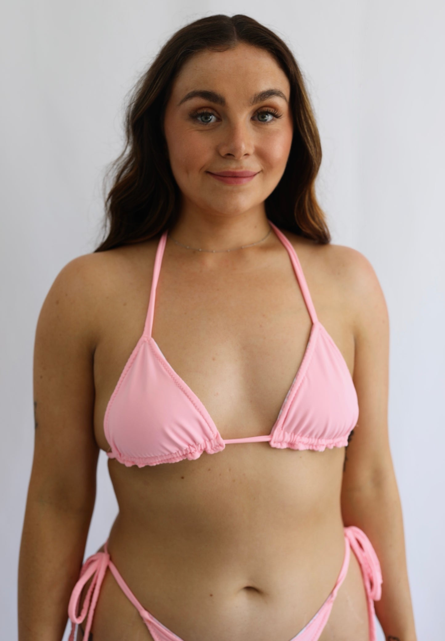 Woman wearing a pink bikini against a plain background