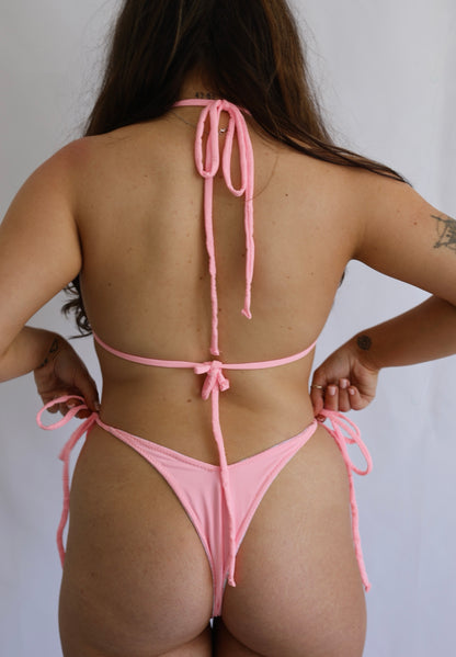 Person wearing a pink bikini against a plain background