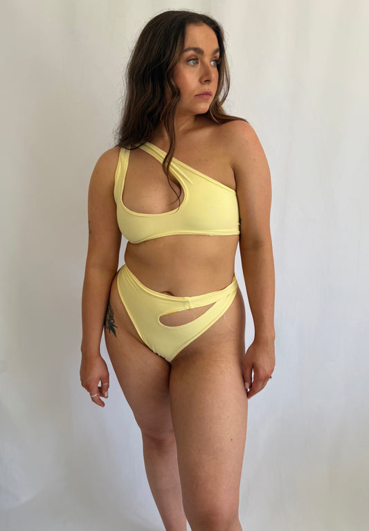 Woman wearing a yellow bikini against a plain background