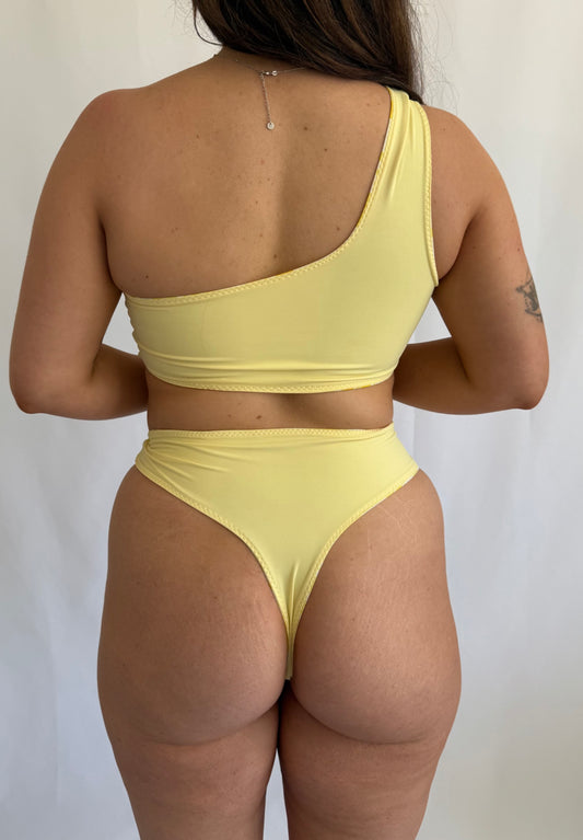 Woman wearing a yellow bikini against a plain background
