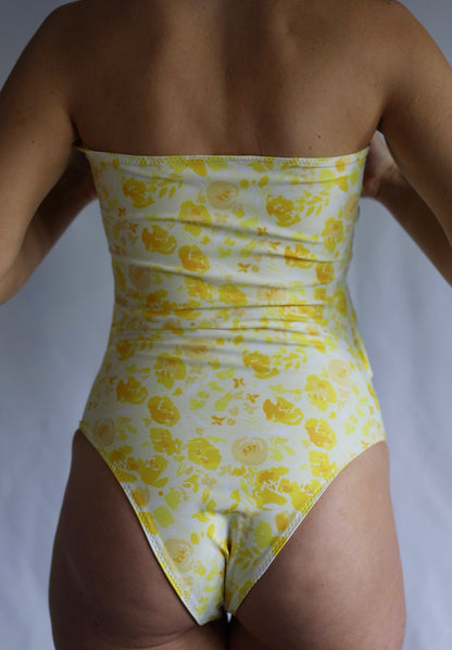 Yellow floral strapless swimsuit on a plain background